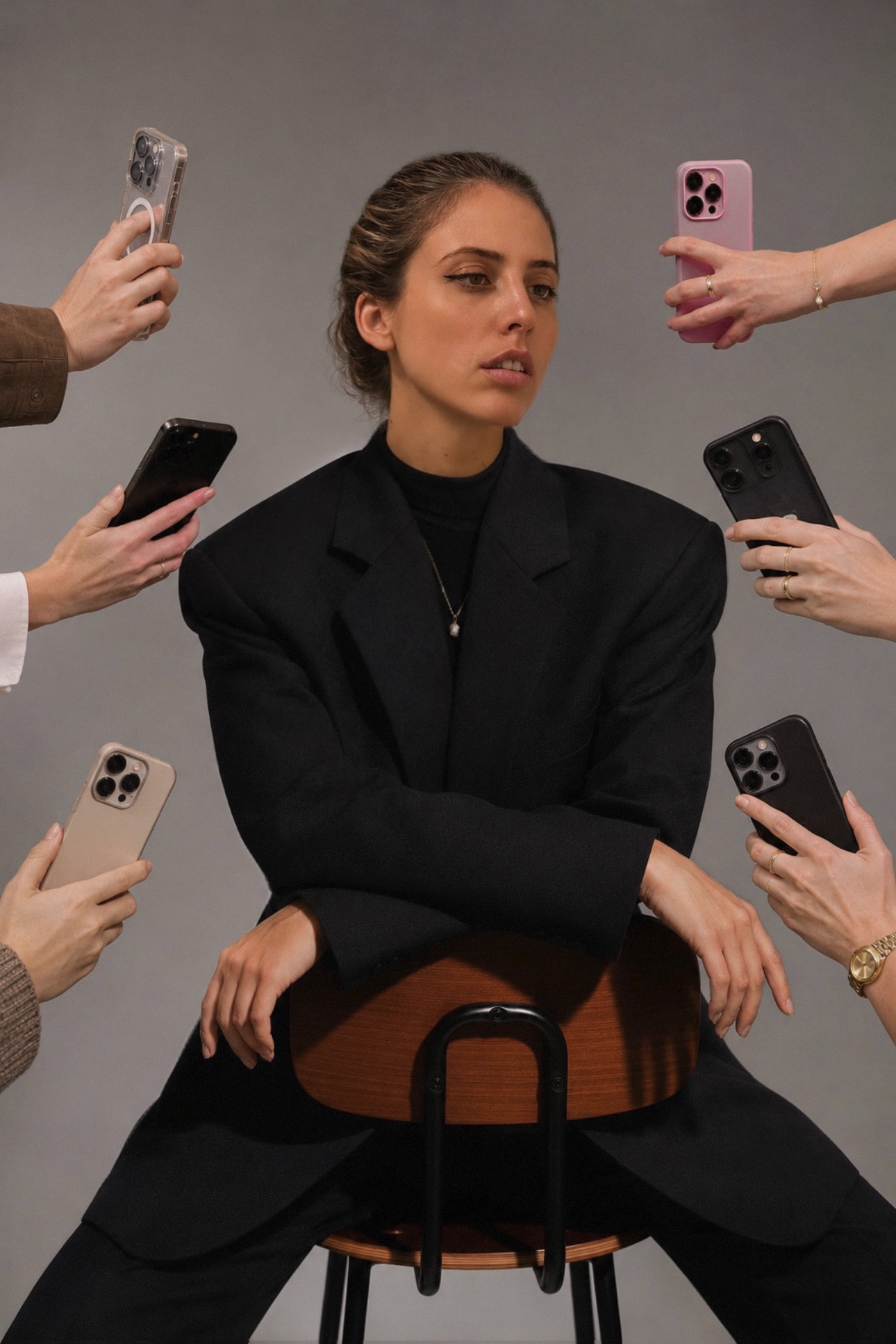 Carlotta Seno seduta su una sedia, circondata da mani che la inquadrano con lo smartphone